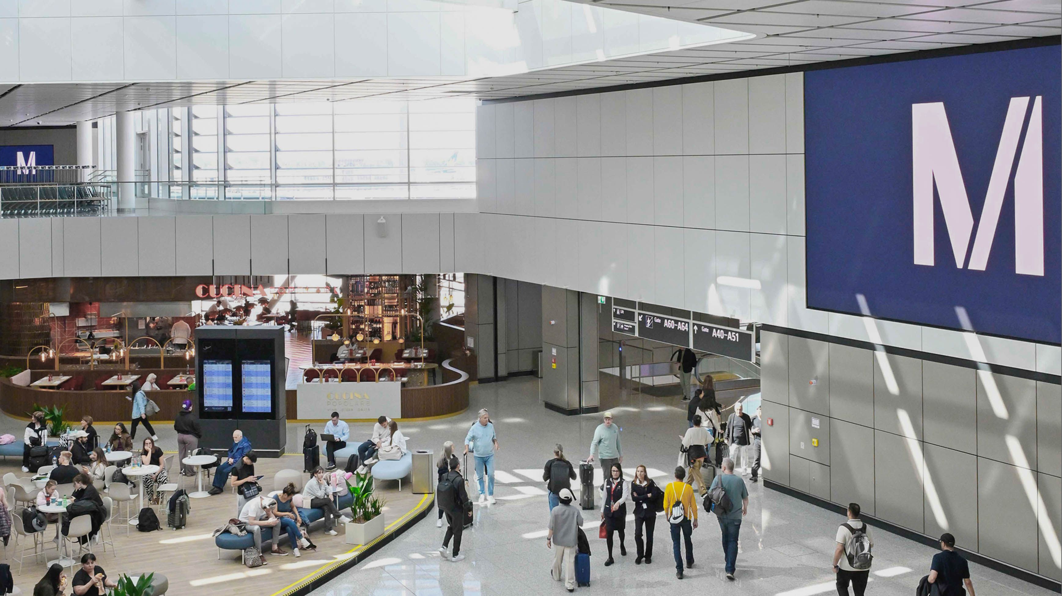 Fotogalerie Terminal 1-Pier Flughafen München: Belebter Terminalbereich am Flughafen München mit Gastronomie, Sitzgelegenheiten und Reisenden mit Gepäck